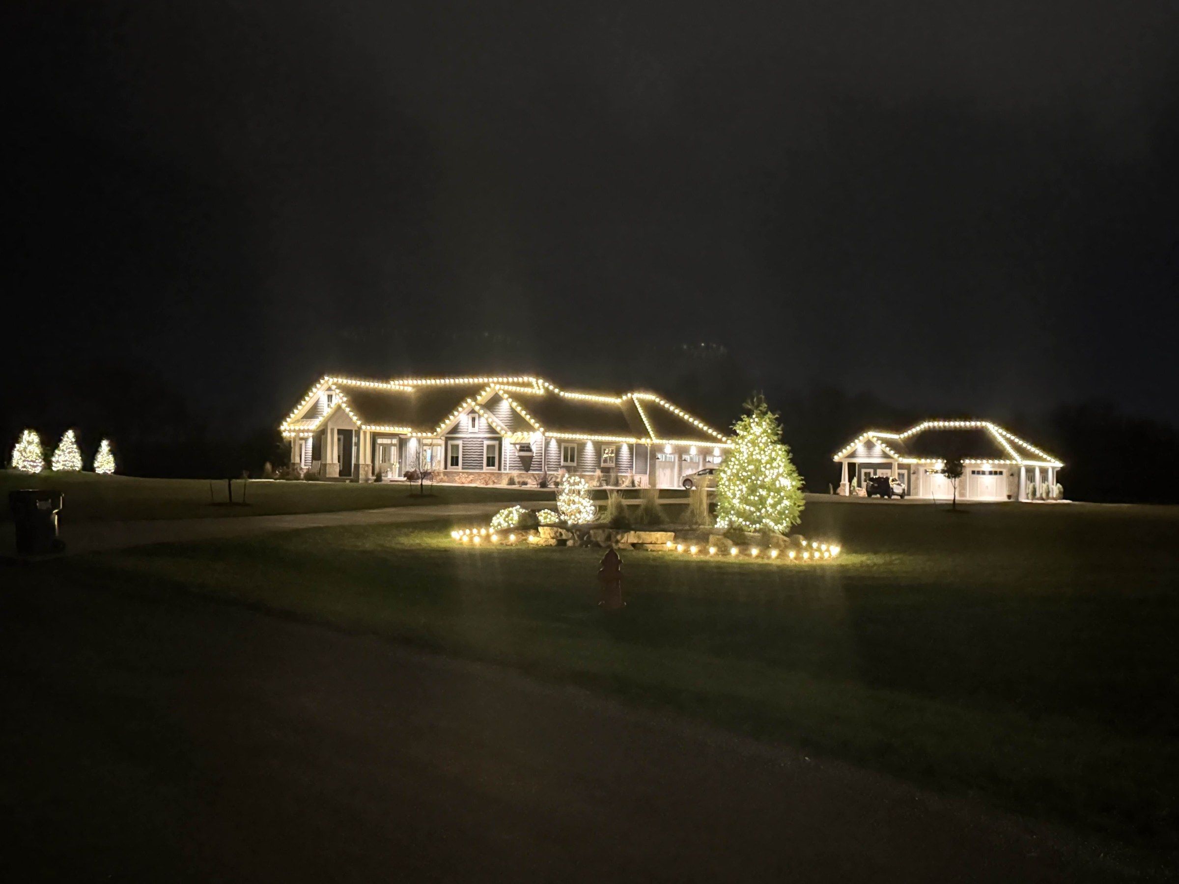 Large ranch home with professionally installed lights on the roofline and trees, done safely from standoff ladders