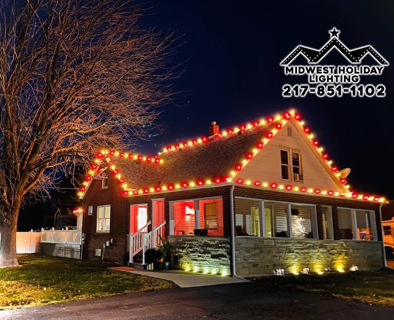 Brick bungalow with alternating red and warm white C9 roofline lights and an uplit stone foundation