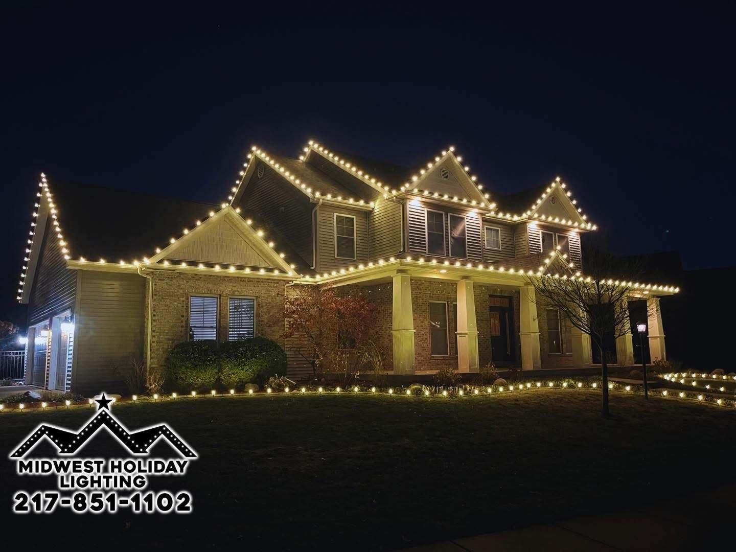 Large two-story home in Central Illinois with warm white C9 Christmas lights outlining every gable, porch roof and landscape bed