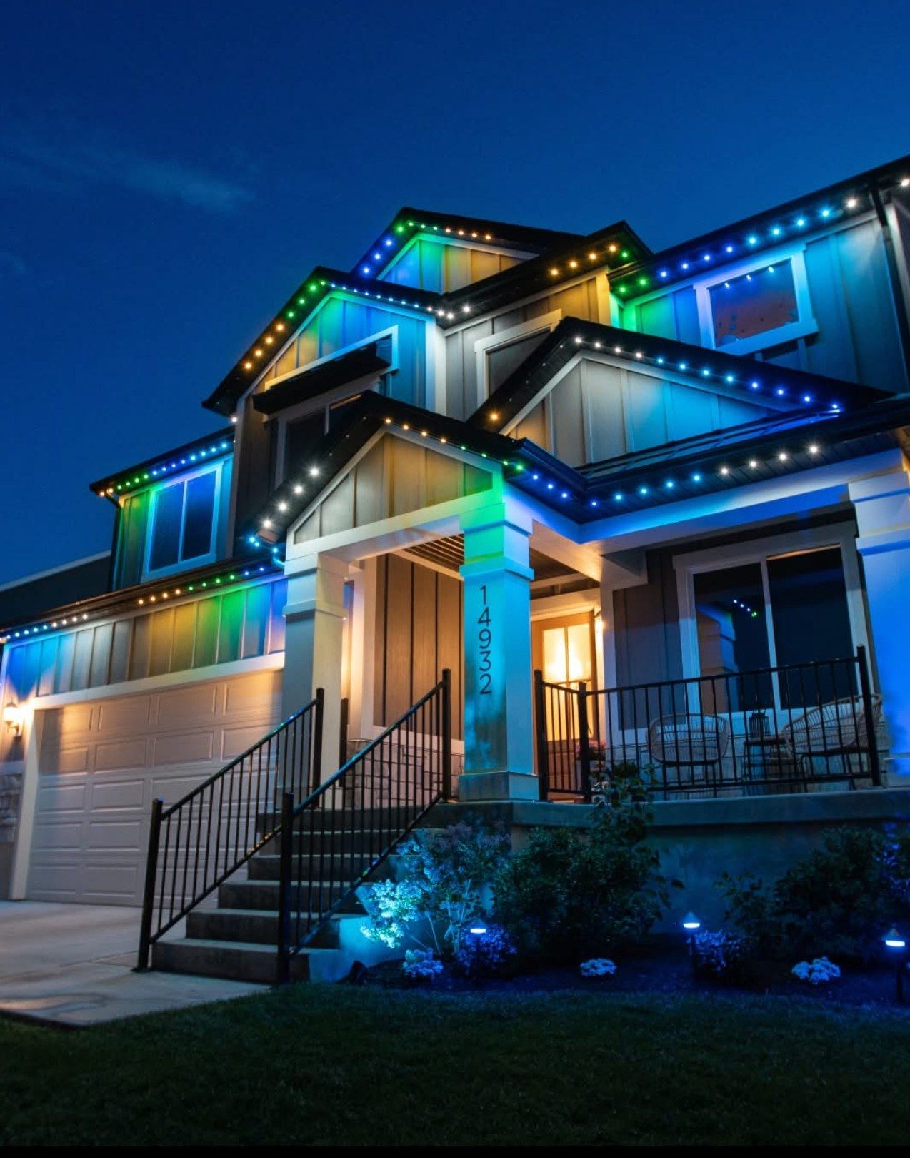 Craftsman-style home lit with permanent LED roofline lights cycling blue, green and warm white