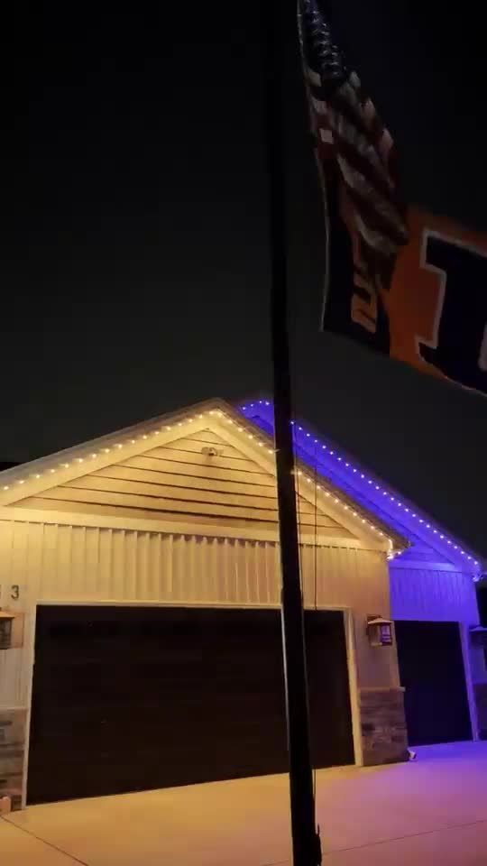 Garage with warm white and blue permanent roofline lights under an Illini flag on a flagpole