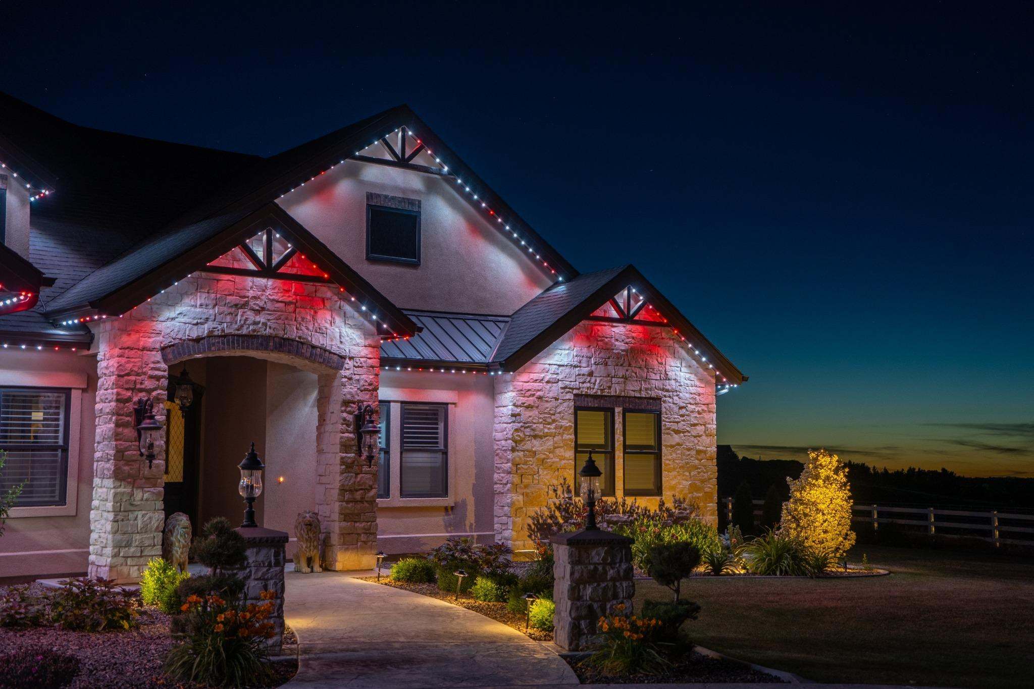 Stone home with permanent Christmas lights glowing red and white along every gable